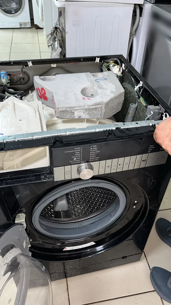 Üst kapağı açılmış çamaşır makinesinde iç aksam kontrolü